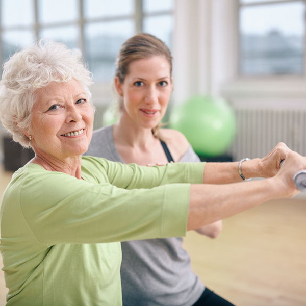 Senior woman exercising with trainer